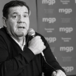 Dirigente habla con micrófono frente a un fondo con el logo de la Municipalidad de General Pueyrredon